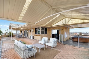 A covered outdoor patio with seating, a barbecue area, and a view of the city. - The Beach House | 4BR, Spa & Jacuzzi near Coogee Beach (Coogee)