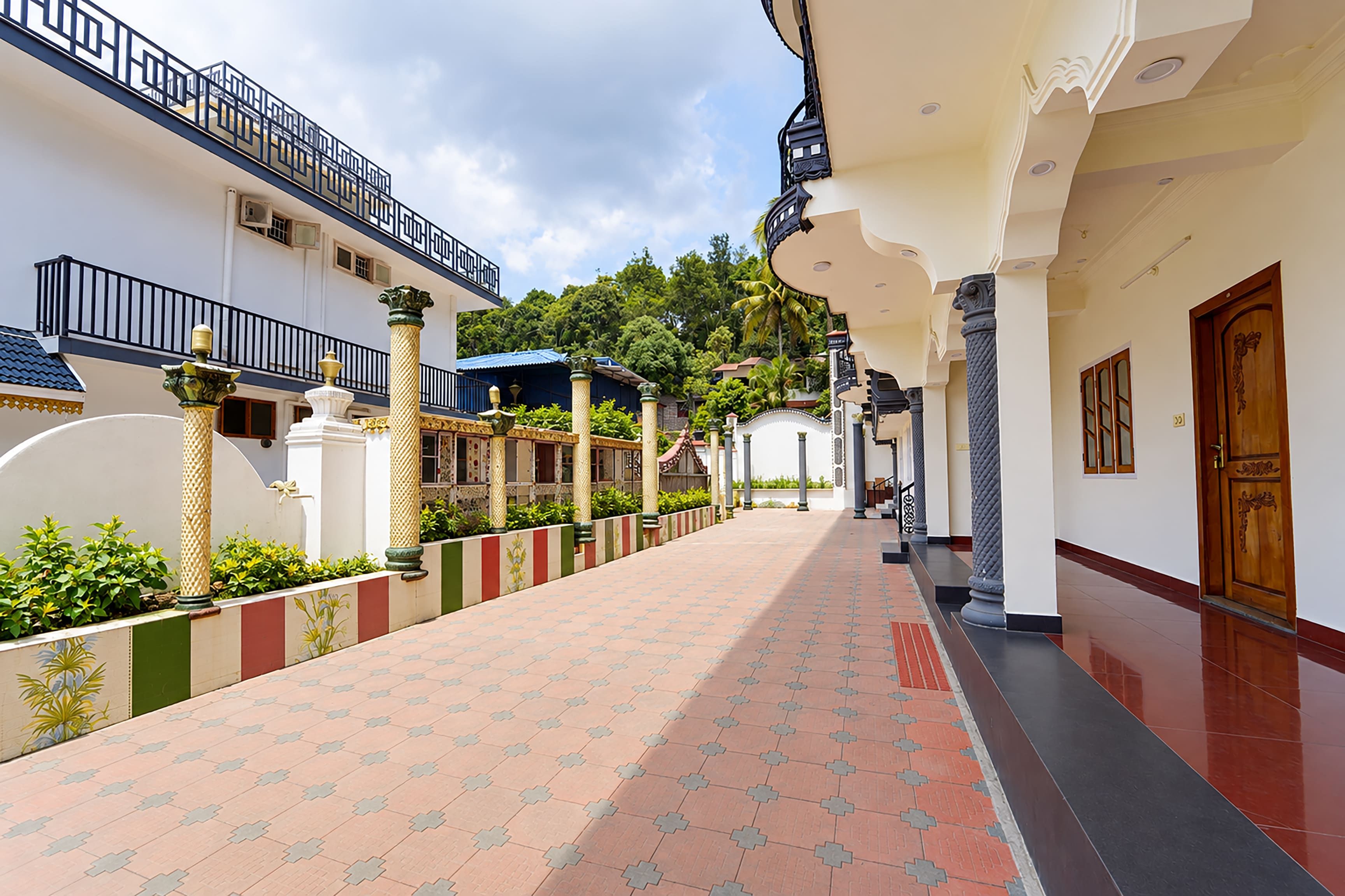 A corridor with tiled flooring, columns, and a wooden door.