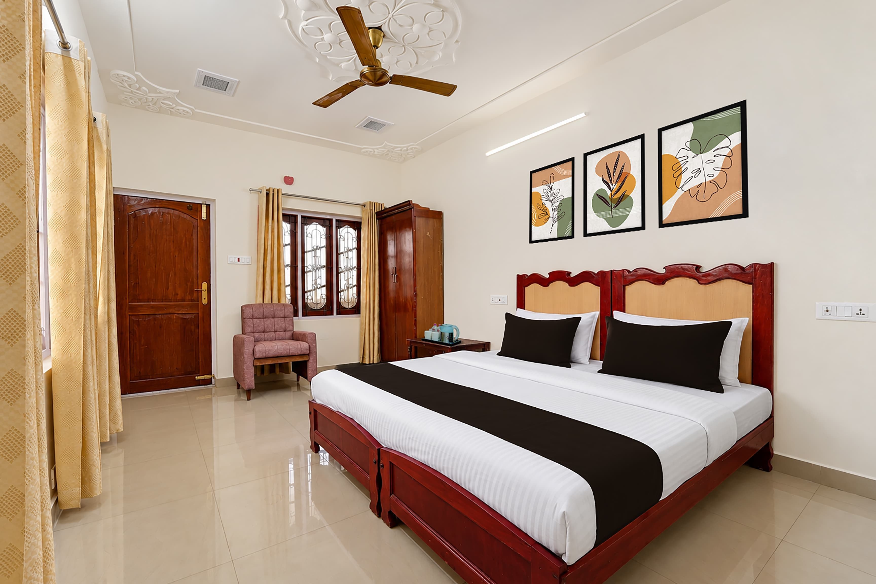 A hotel room with a bed, a chair, a desk, and a ceiling fan.