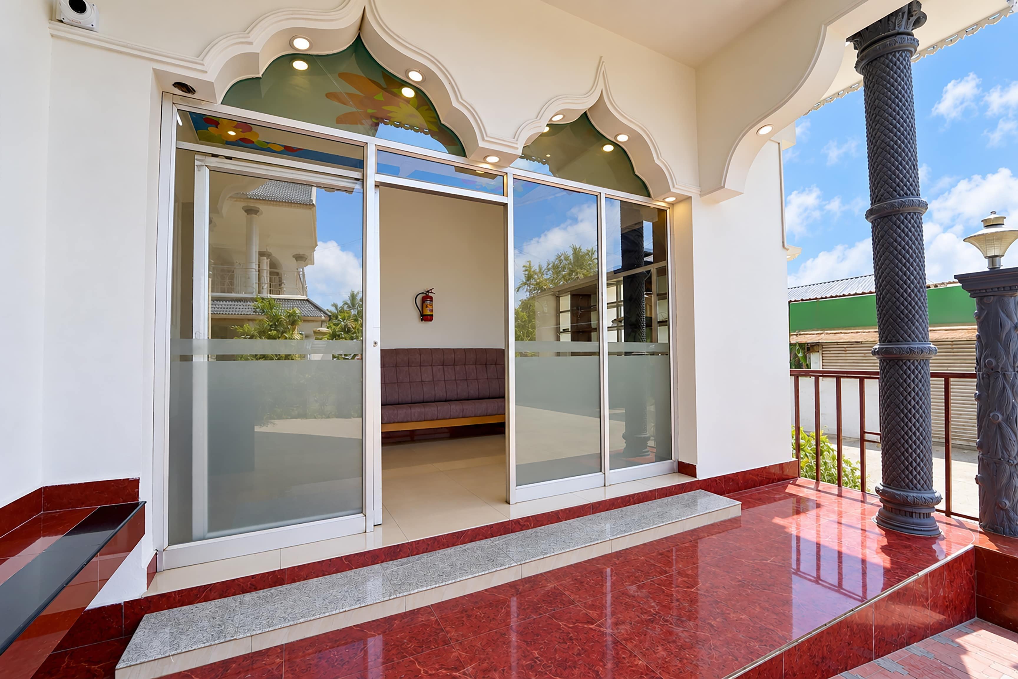 A hotel entrance with a glass door, a bench inside, and a tiled floor.
