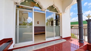 A hotel entrance with a glass door, a bench inside, and a tiled floor.