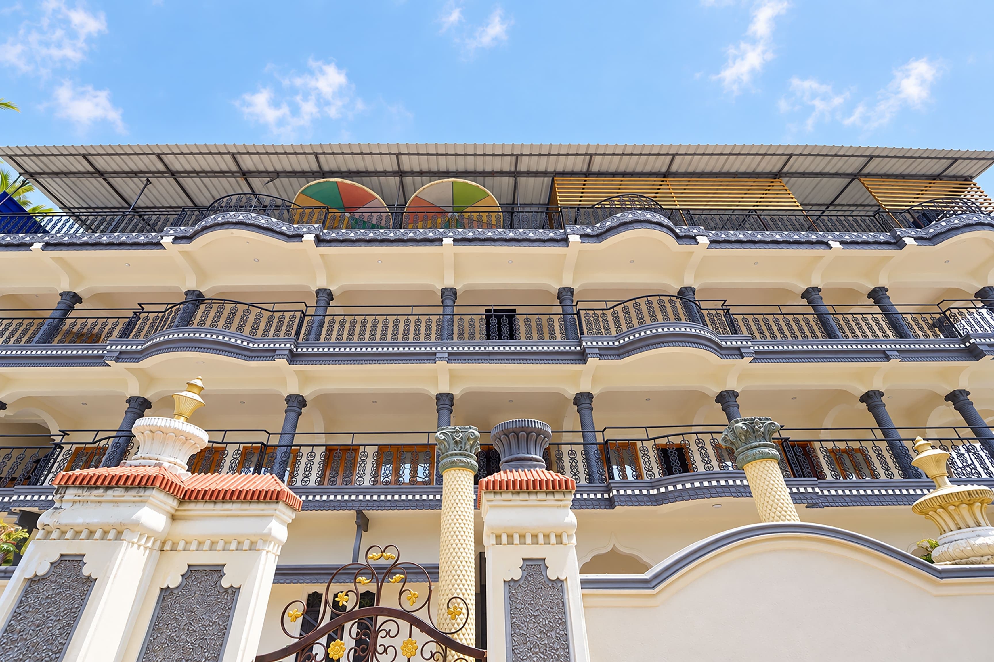 Un edificio de varios pisos con balcones, columnas decorativas y un tejado de tejas.