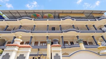 Un edificio de varios pisos con balcones, columnas decorativas y un tejado de tejas.