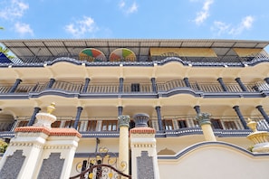 A multi-story building with balconies, decorative columns, and a tiled roof. - Collection O Periyar National Park (Thekkady)