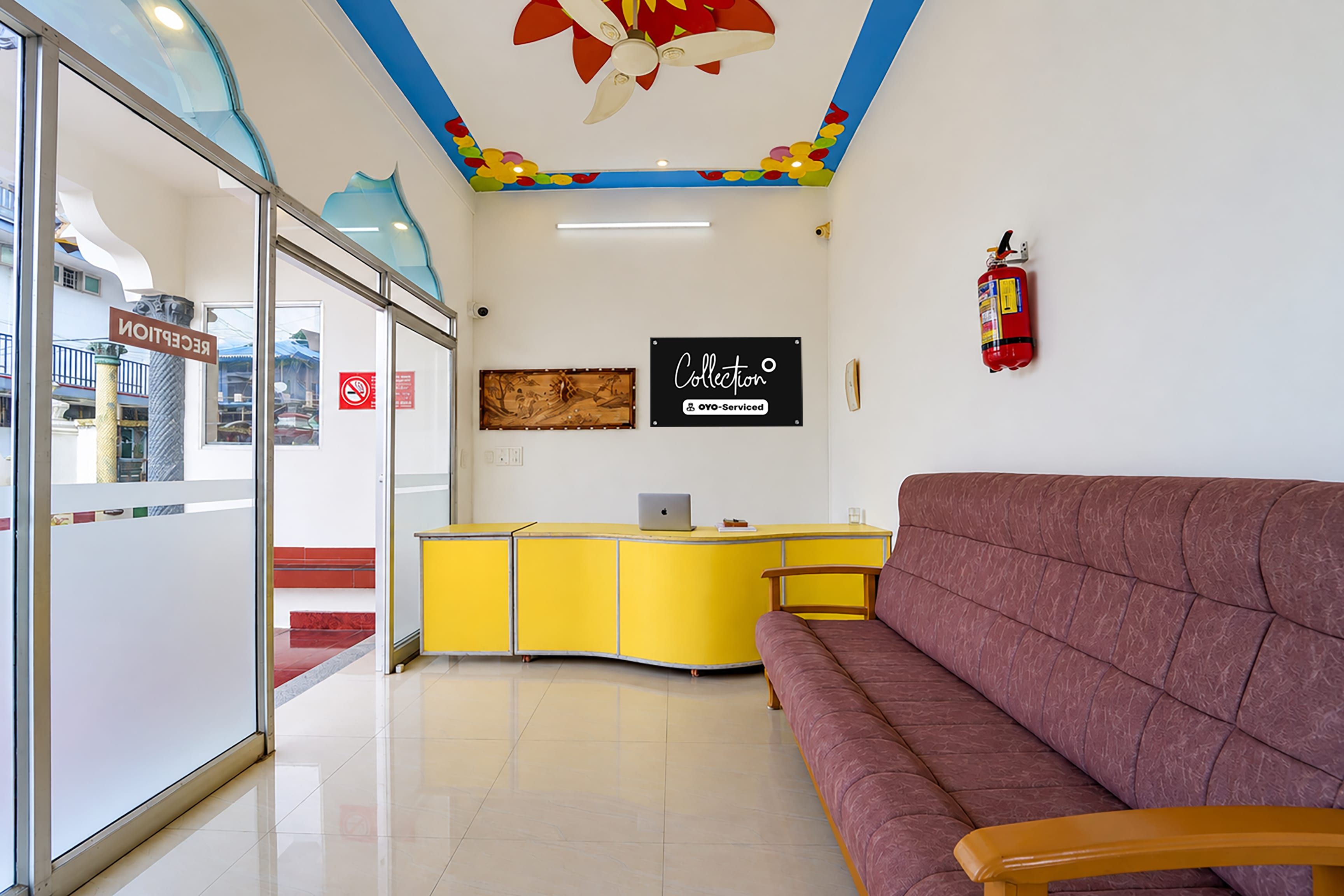 A reception area with a yellow desk, a red couch, and a fire extinguisher on the wall.
