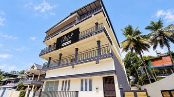 Um edifício de vários andares com varanda no andar superior, placa indicando que é administrado pela OYO e entrada com portão.