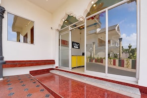 A hotel entrance with a reception desk, a glass door, and a tiled floor. - Collection O Periyar National Park (Thekkady)