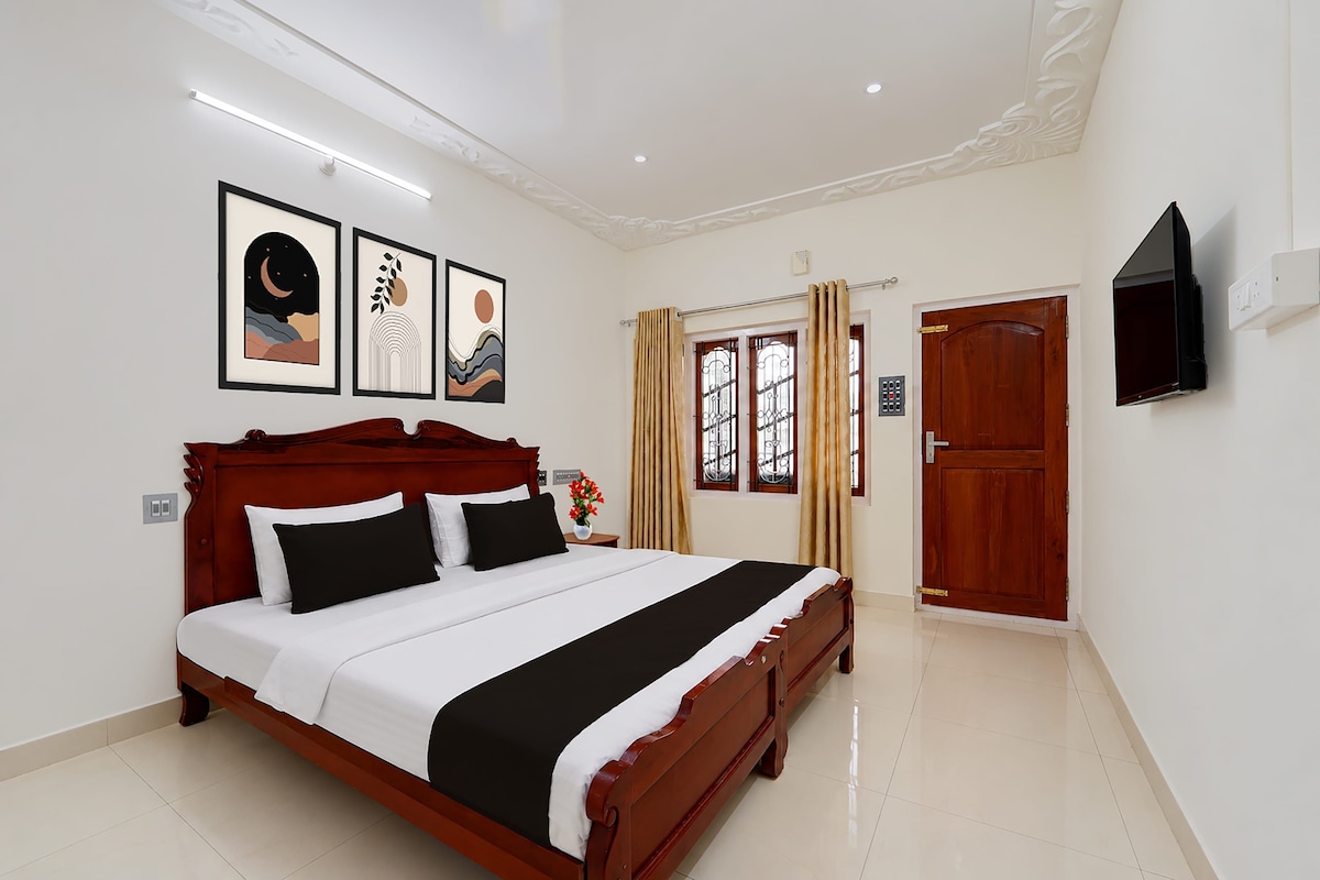 A hotel room with a large bed, a flat-screen TV mounted on the wall, and artwork above the bed.