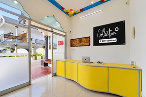 Un área de recepción con un mostrador amarillo, una computadora portátil y un letrero que dice 'Collection oyo-Serviced'.