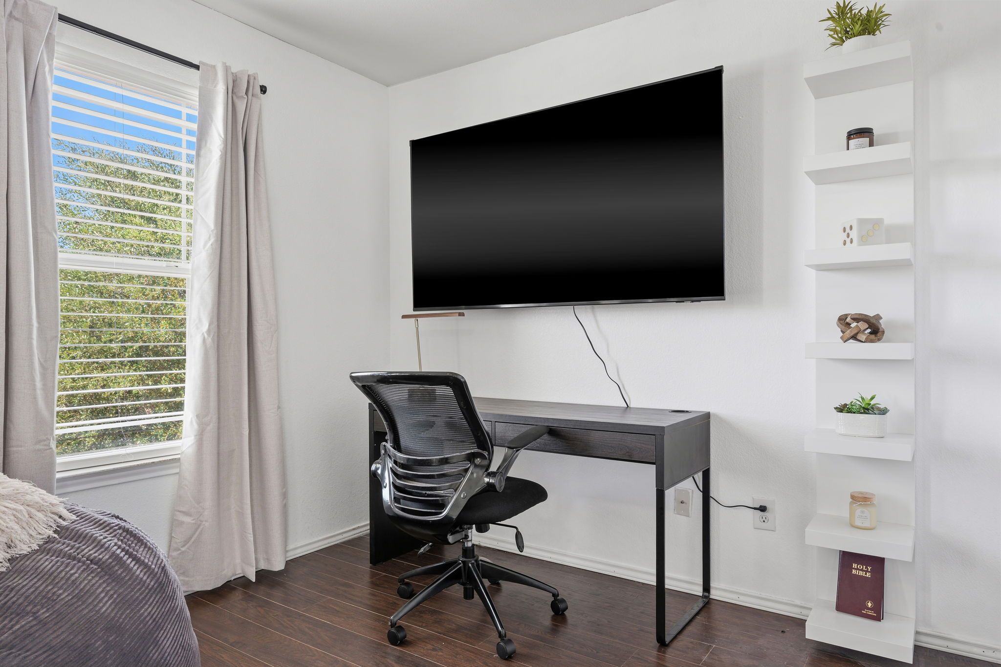 A modern office space with a desk, chair, and a mounted TV.