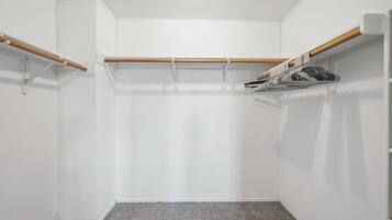 A corner closet with a wooden rod and a metal rack for hanging items.