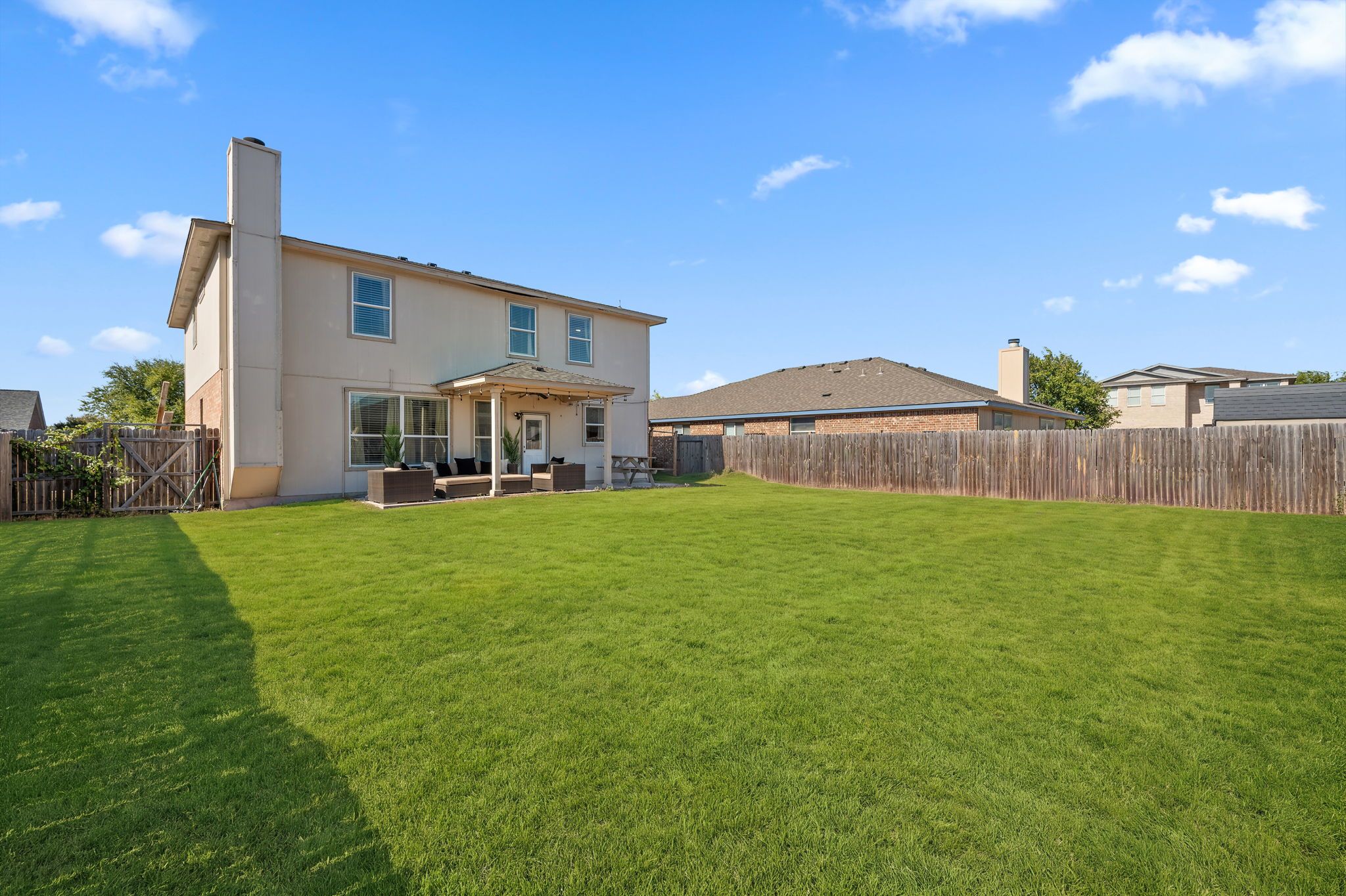 A two-story house with a covered patio and a fenced backyard.