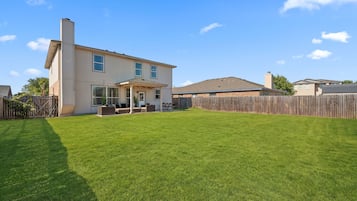 A two-story house with a covered patio and a fenced backyard.