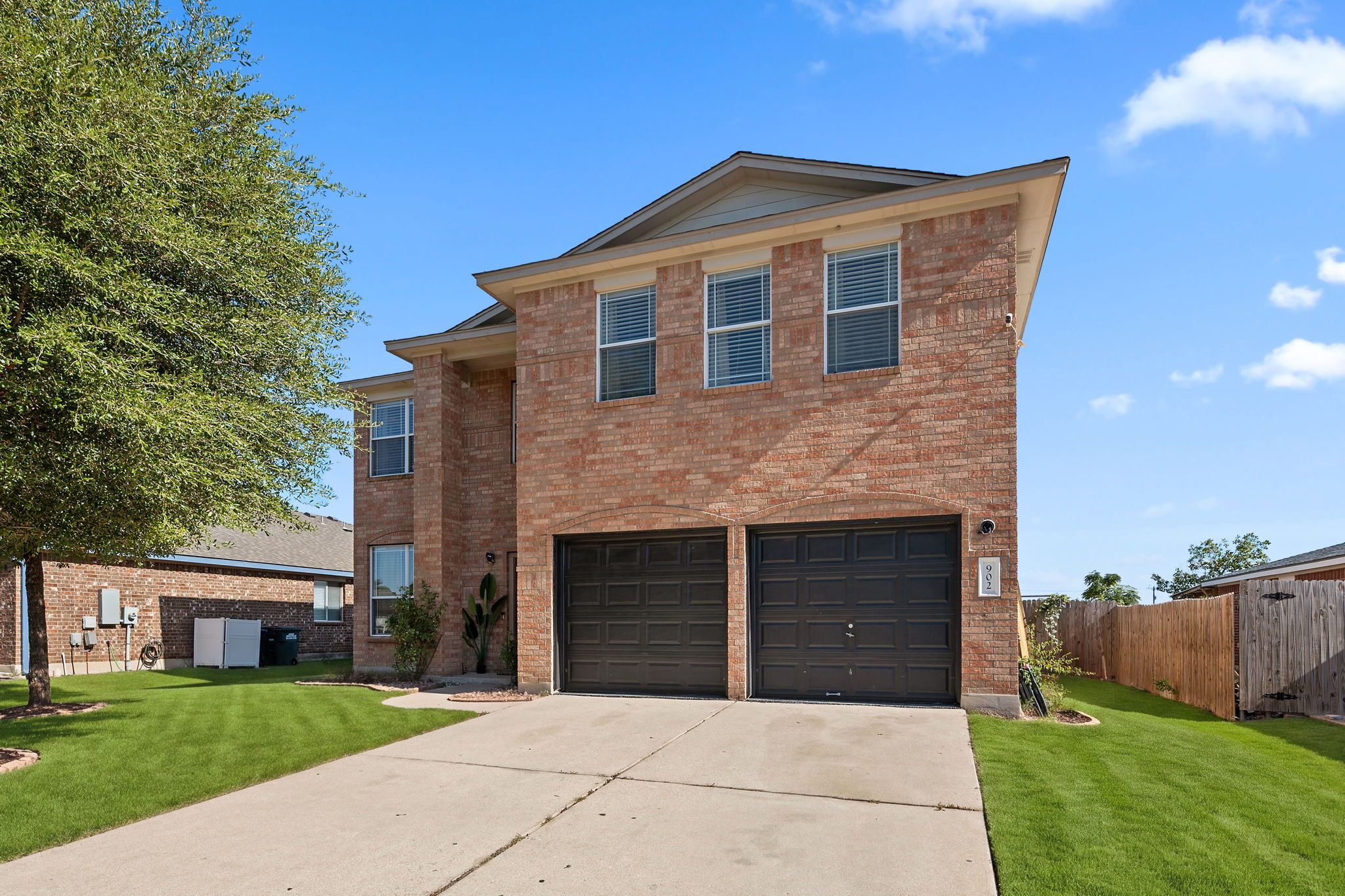 A two-story brick house with a front garage and a well-maintained lawn.