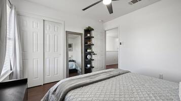 Une chambre à coucher avec un lit, un ventilateur de plafond, une armoire et un miroir.