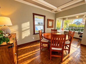 A dining area with a round table, wooden chairs, a lamp, and a view of the outdoors. - Historic Puget Sound Waterfront • Capitol + Marina View • Walk to Farmers Market (Olympia)
