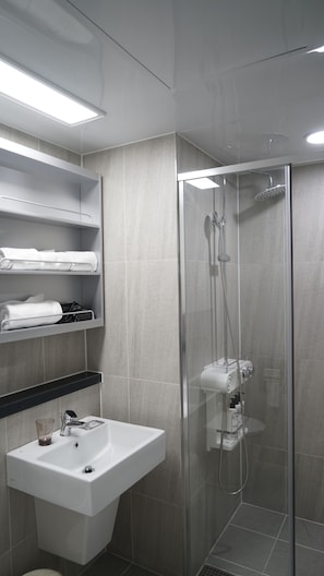 A modern bathroom with a glass-enclosed shower, a white sink, and a towel rack. - remainzhotel (Incheon)
