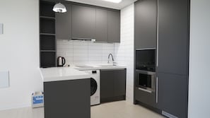 A modern kitchen with a built-in washer, a sink, and a microwave. - remainzhotel (Incheon)