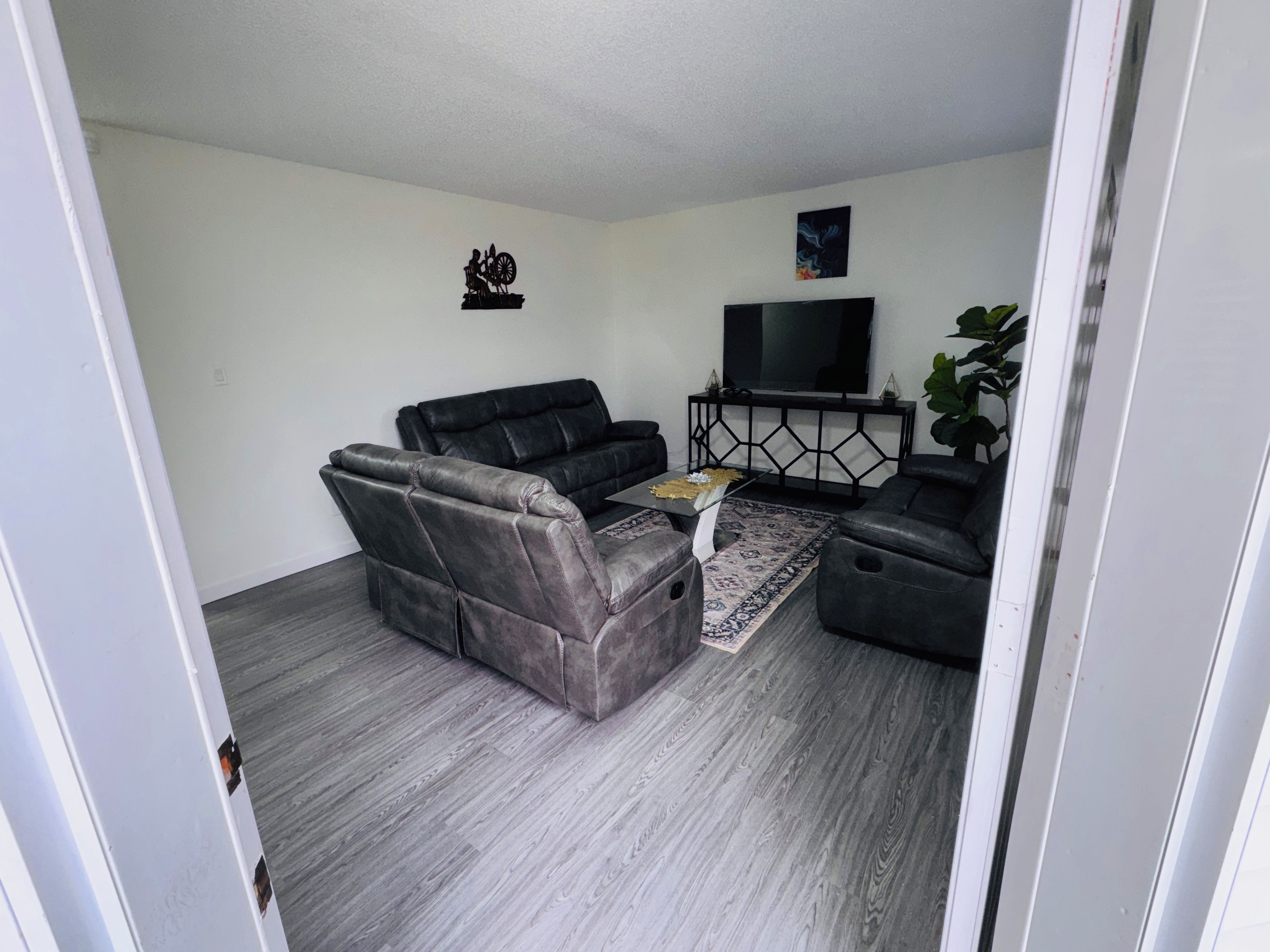 A living room with a sofa, armchairs, a coffee table, a TV, and a decorative wall piece.
