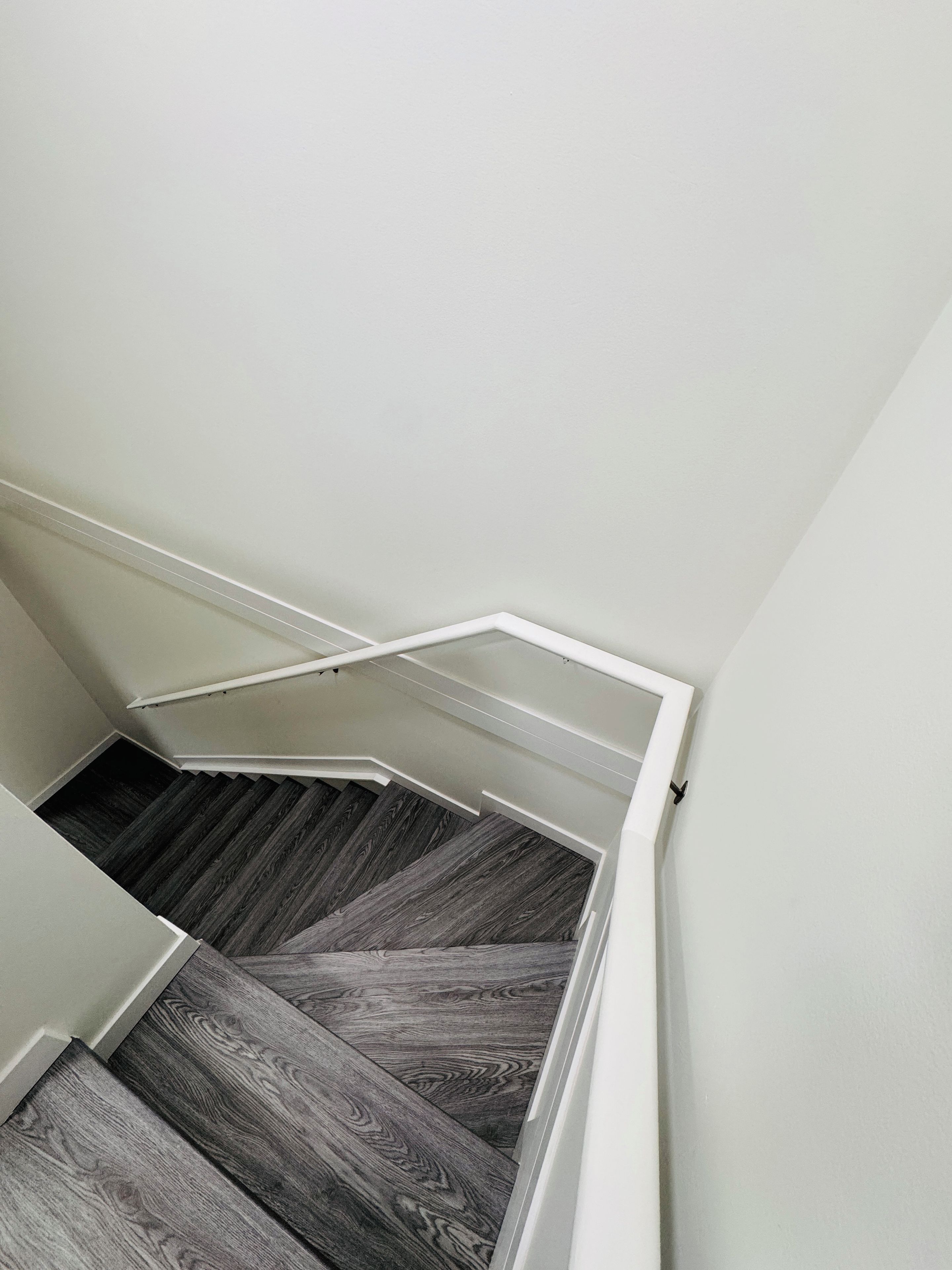 A staircase with a wooden floor and white walls.