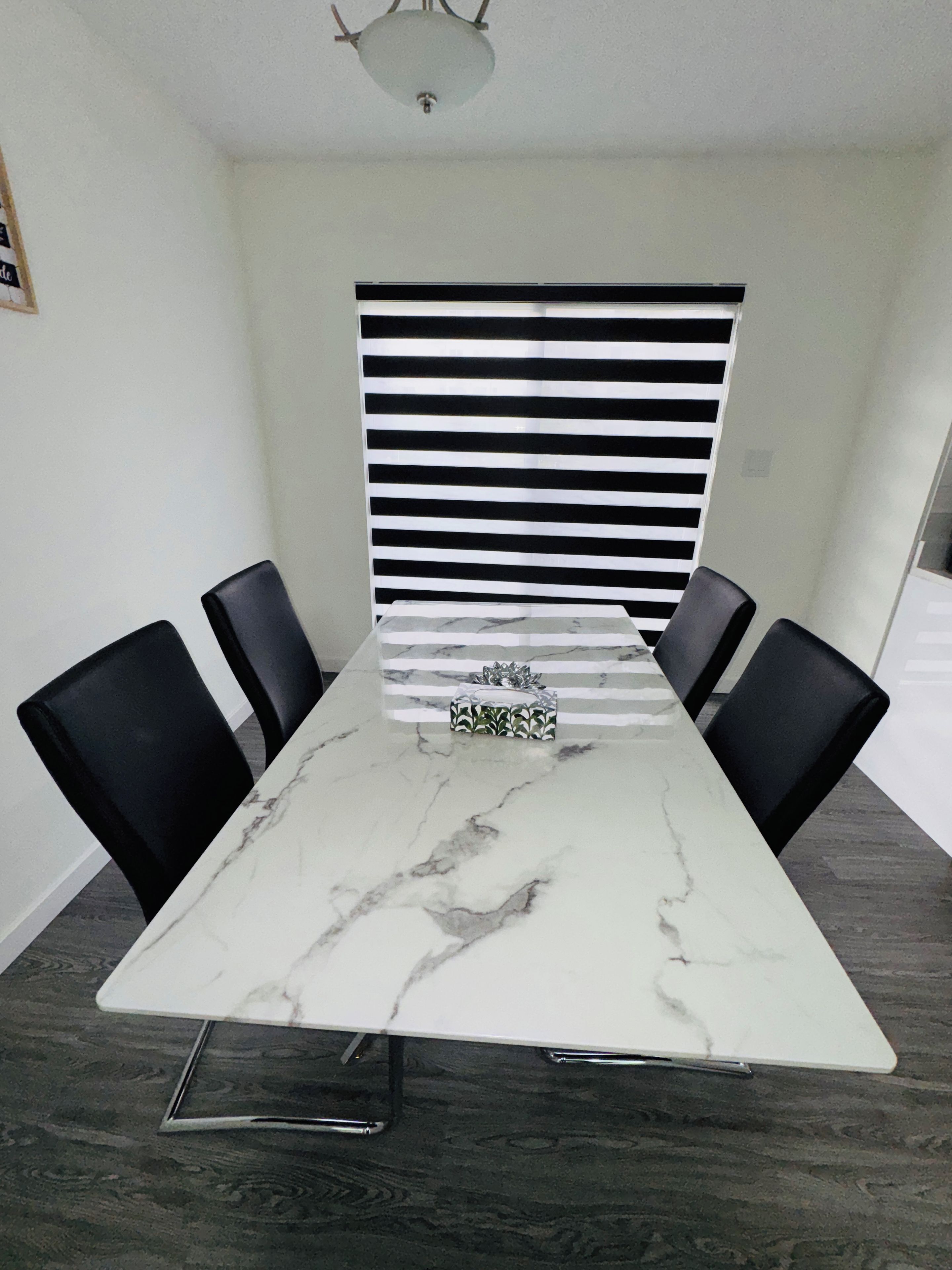 A conference room with a marble table, black chairs, and a black and white striped partition.