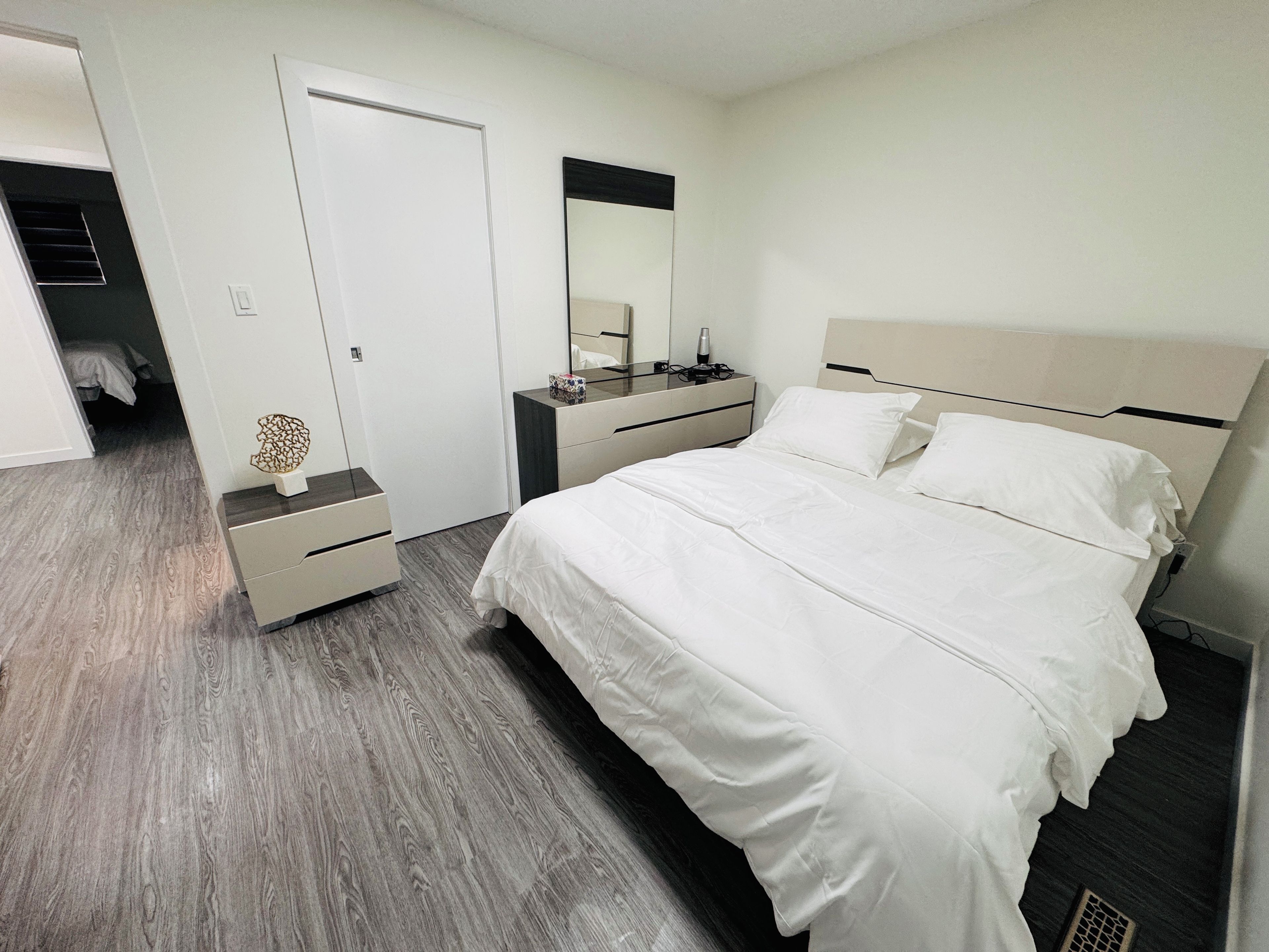 Ein modernes Schlafzimmer mit einem großen Bett, Nachttischen, einer Kommode und einem Spiegel.