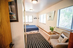 A bedroom with a bed, a chair, a window with blinds, a rug, and a framed picture on the wall. - Charming 5-bedroom house in South Lake Tahoe perfect for families (South Lake Tahoe)