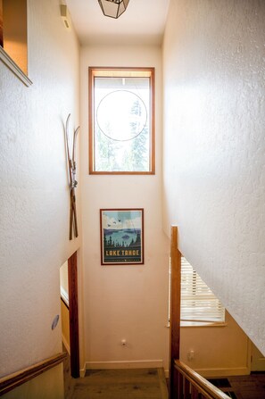 A narrow stairway with a framed picture of Lake Tahoe and a window above. - Charming 5-bedroom house in South Lake Tahoe perfect for families (South Lake Tahoe)