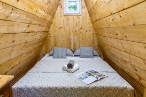 A small, wooden room with a bed, pillows, a window, and a magazine on the bed. - Paradise Forest Glamping near Koper Hut 4, Koper, Slovenia (Koper)