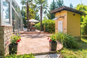 A patio area with a wooden deck, potted plants, and a small yellow building with a door and window. - Paradise Forest Glamping near Koper Hut 4, Koper, Slovenia (Koper)