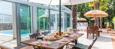 An outdoor dining area with a table set for breakfast, surrounded by chairs and umbrellas.