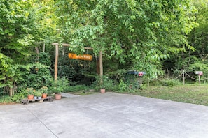 Ein gepflasterter Parkplatz mit einem Holzschild, das einen Glamping-Platz kennzeichnet.