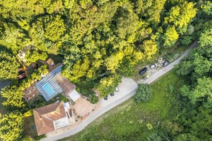 An aerial view of a property with a swimming pool, a covered patio, and a road with parked cars. - Paradise Forest Glamping near Koper Hut 2, Koper, Slovenia (Koper)