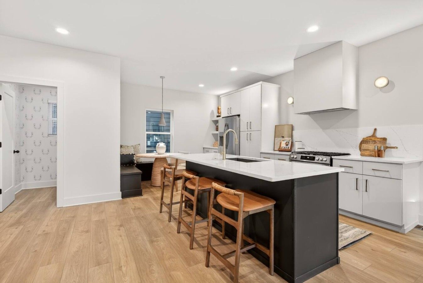 A modern kitchen with a central island, bar stools, and a built-in oven.