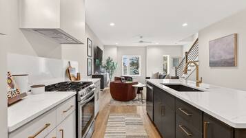 A modern kitchen with a central island, a dining area with a sofa, and a staircase with a view.