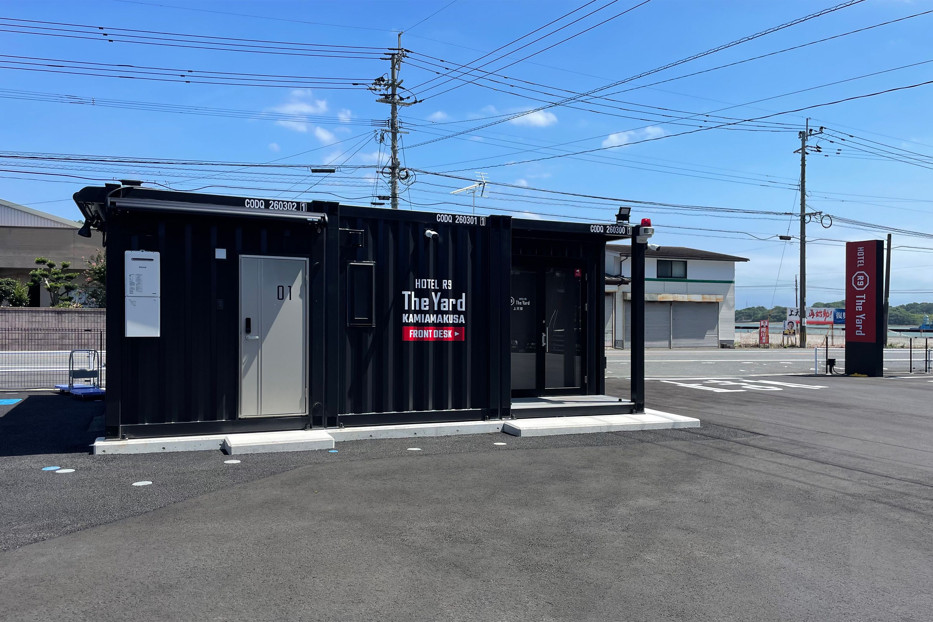 A black hotel container with 'The Yard' branding, a front desk, and a sign for 'Hotel R9'.