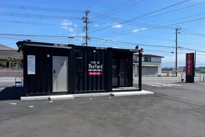 Een zwarte hotelcontainer met branding 'The Yard', een receptie en een bord met 'Hotel R9'.
