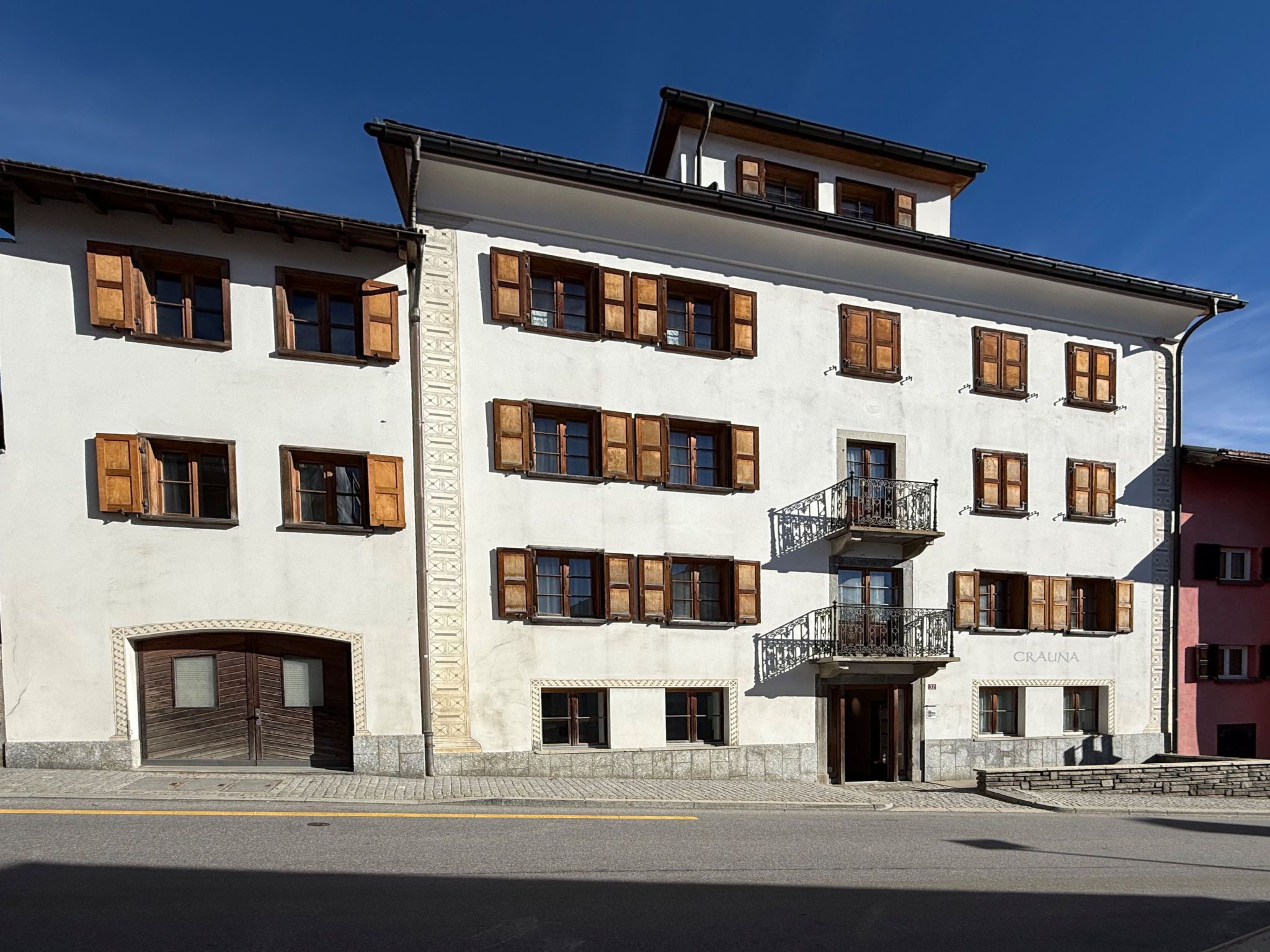 A multi-story building with a central entrance, a balcony with wrought iron railings, and a sign that reads 'CRAUNA'.