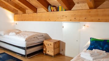 A bedroom with a bed, a bedside table, a wardrobe, and a shelf with books.