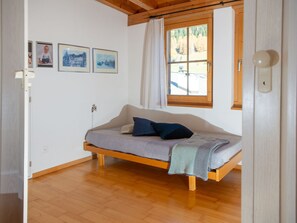 Une petite pièce agréable, dotée d’un lit simple, d’une fenêtre avec des rideaux et de quelques tableaux encadrés accrochés au mur.