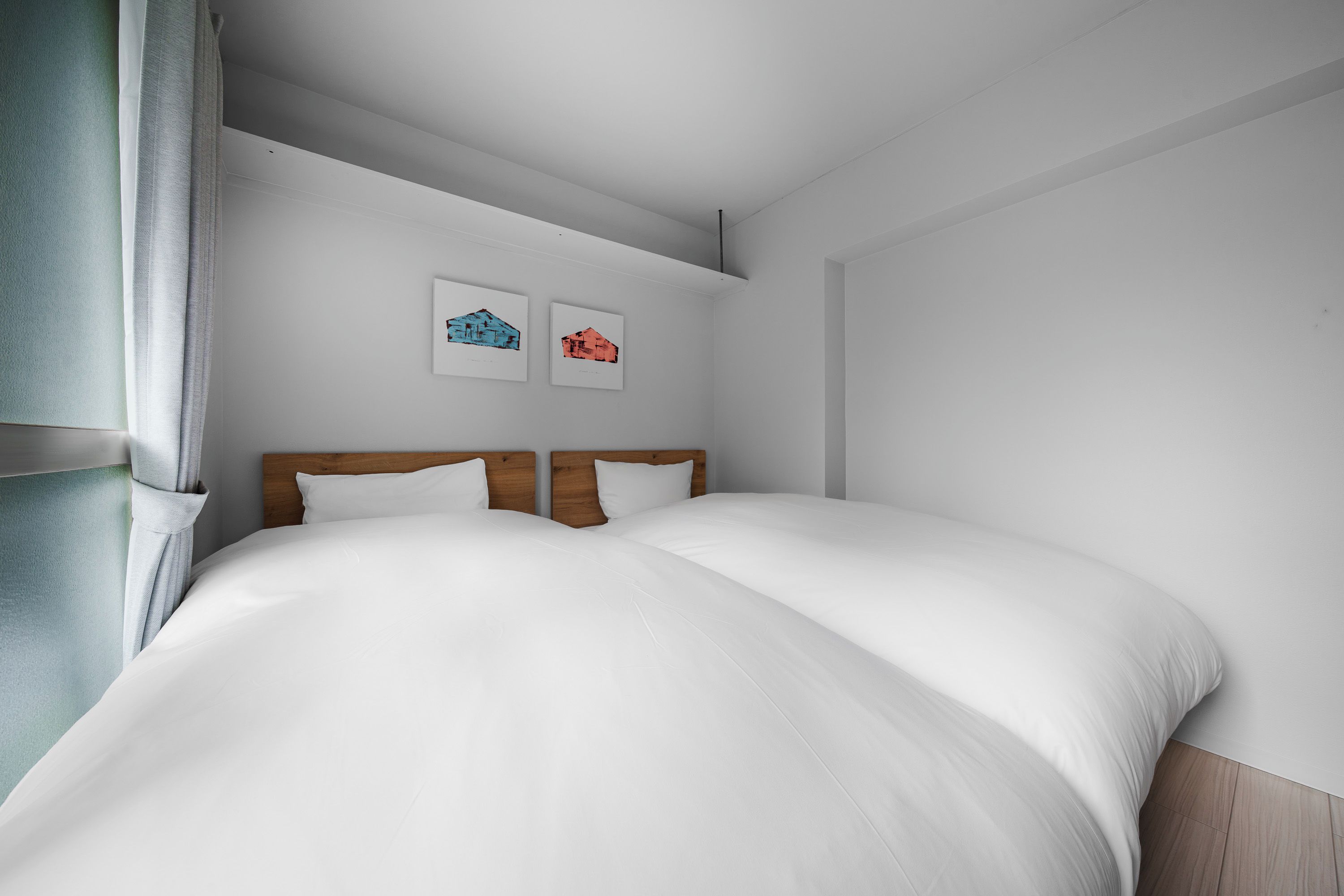 A modern bedroom with a large bed, wooden headboard, and two wall-mounted artworks.