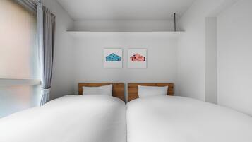 Cama doble con cabecera de madera, ropa de cama blanca y dos cuadros en la pared.