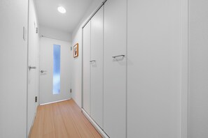 A hallway with a wooden floor, white walls, and a door with a frosted glass panel. - Billboard 101 (Sapporo)