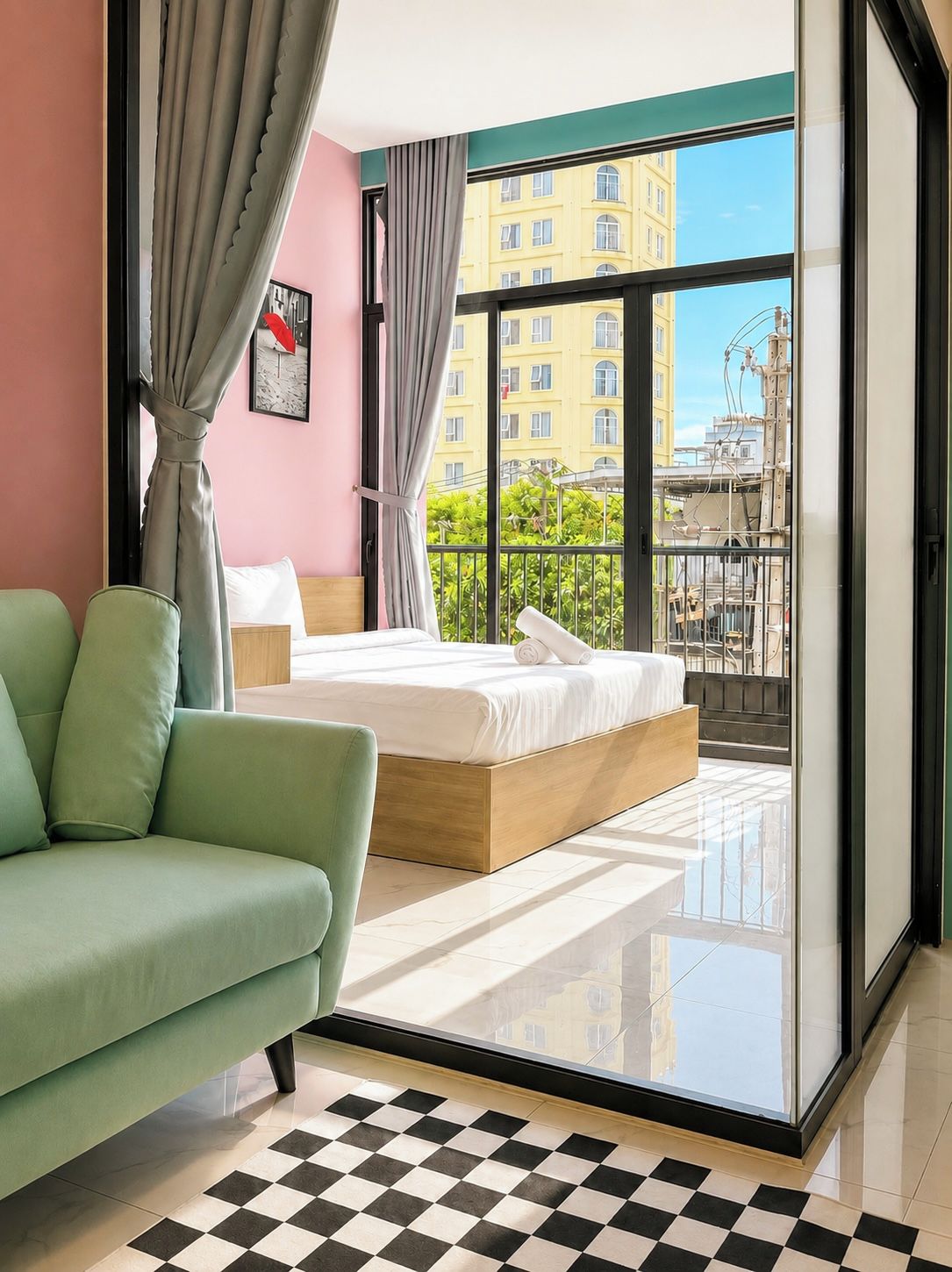 A modern bedroom with a large bed, a green sofa, and a view of a building through a large window.