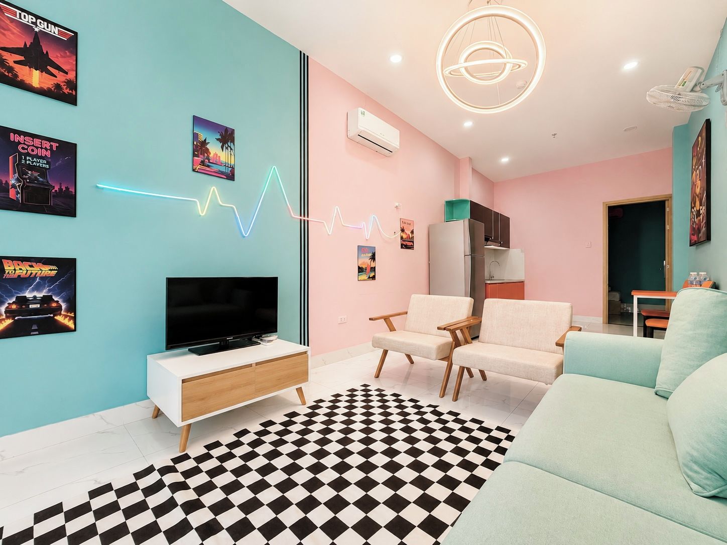 A modern living room with a flat-screen TV, two armchairs, a sofa, a patterned rug, and wall art.