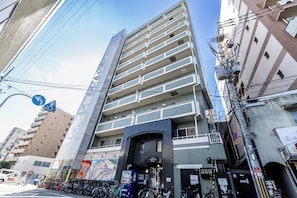 A multi-story building with a ground-level entrance, a vending machine, and a bicycle parking area. - Ocean Imamiyaebisu Ekimae (Osaka)