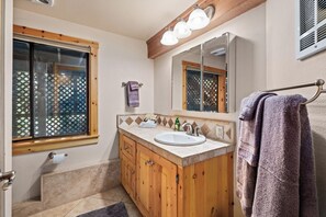 A bathroom with a wooden vanity, a sink, a mirror, and a window with a lattice design. - Unique 3-bedroom home in charming Carnelian Bay-North Lake Tahoe, CA (Carnelian Bay)