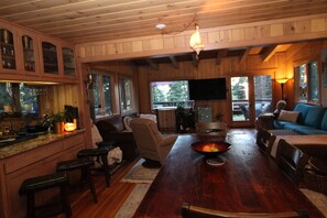 A wooden interior with a dining table, chairs, a sofa, and a television. - Unique 3-bedroom home in charming Carnelian Bay-North Lake Tahoe, CA (Carnelian Bay)