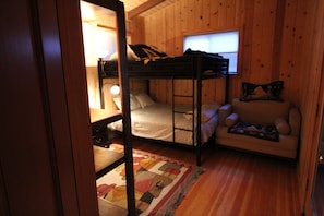 Une chambre avec un lit superposé, un bureau et un canapé.