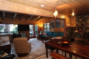 L’intérieur d’un chalet chaleureux, avec une table à manger en bois, un canapé et une cheminée.